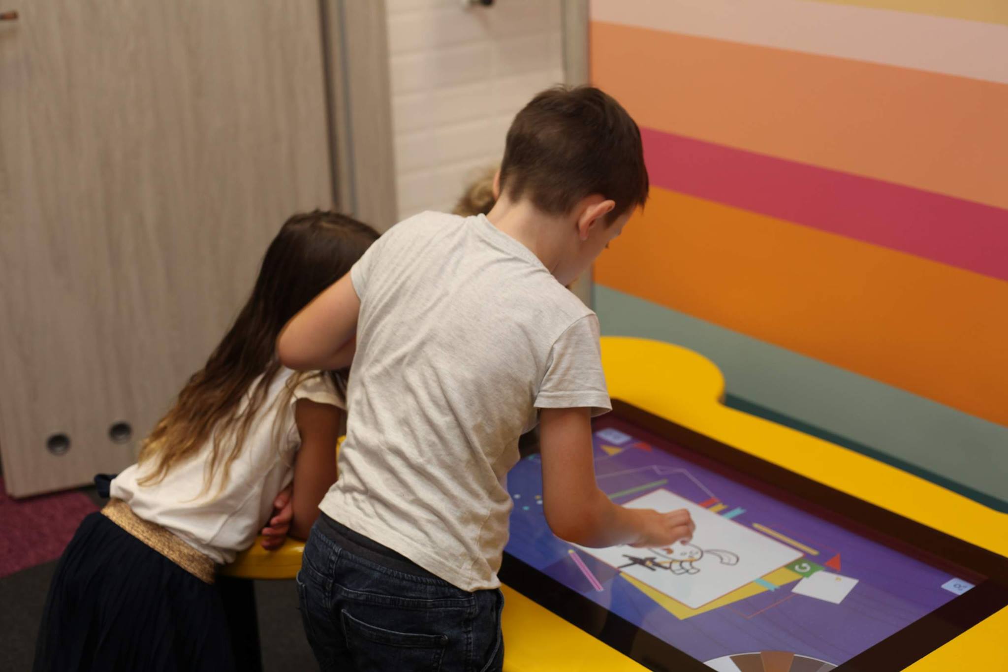 dzieci bawiące się przy stole interaktywnym w malowanki